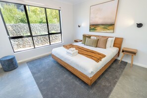 A modern bedroom with a large bed, a window with a view, a painting on the wall, and a small side table. - MAGNIFICENT AND OPULENT 5 BEDROOM OASIS BOASTING SWEEPING VALLEY VIEWS (Yallingup)