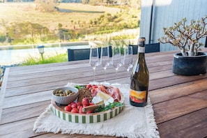 A wooden table with a charcuterie board, wine bottle, and glasses. - MAGNIFICENT AND OPULENT 5 BEDROOM OASIS BOASTING SWEEPING VALLEY VIEWS (Yallingup)