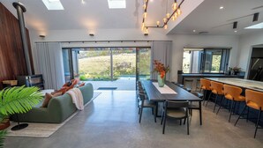 Un ambiente moderno con zona pranzo, cucina e un'ampia porta-finestra scorrevole che dà su uno spazio esterno.