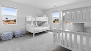 Quarto branco com beliches, berço e dois pufes.