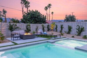 A pool area with a fire feature, lounge chairs, and a view of palm trees and mountains. - 4 Bedroom Luxury Estate With Pool Spa Firepit (Indio)
