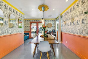 A dining area with a long table, chairs, and a hanging light fixture. - Spirit of Sofia 23 Bedroom Epic Resort (Palm Springs)