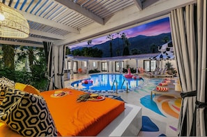 A pool area with a view of mountains, a covered seating area, and a dining setup with a pineapple. - Spirit of Sofia 23 Bedroom Epic Resort (Palm Springs)