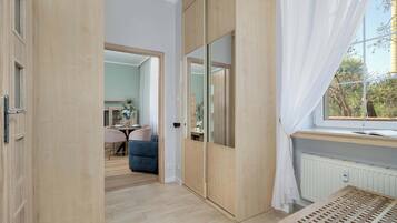 A room with a sliding door, a window with curtains, a radiator, and a table.