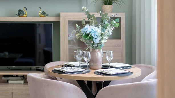 Une table à manger ornée d’un vase de fleurs, de verres à vin et de couverts.