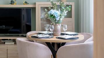 A dining table with a vase of flowers, wine glasses, and cutlery.