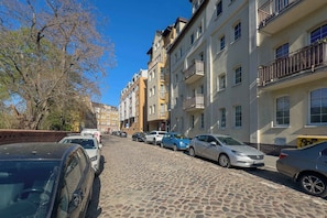 A cobblestone street lined with multi-story buildings, parked cars, and a tree. - Modern Studio Near the Old Market Square | Near the Warta River | Smart TV (Poznań)