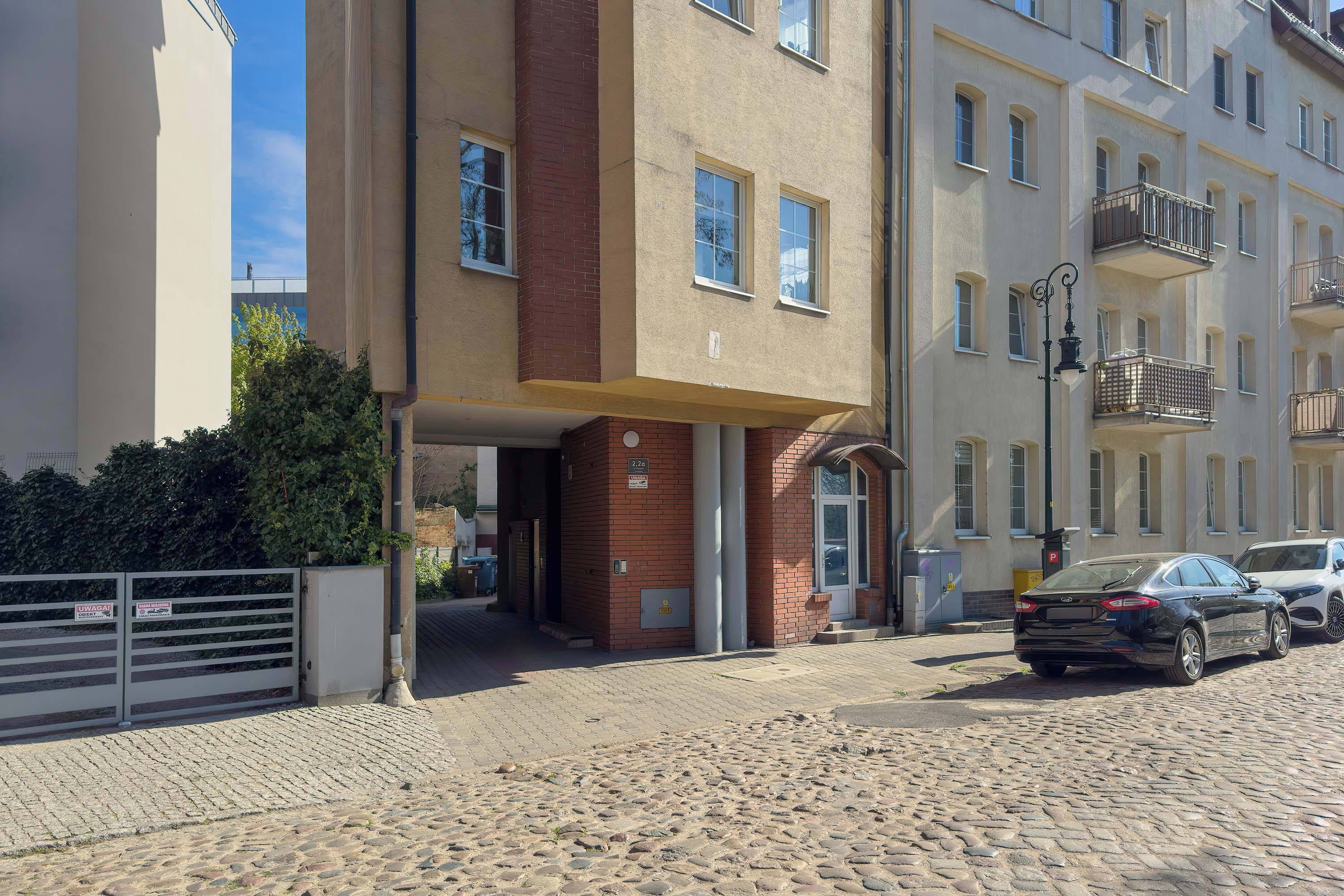 A building with a brick entrance, a gated driveway, and a parked car.