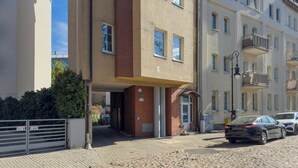 Un bâtiment avec une entrée en briques, une allée bordée de portails et une voiture garée.