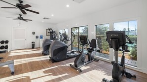 A gym with ceiling fans, exercise equipment, and large windows with a view. - Romar House 203A by Liquid Life (Orange Beach)