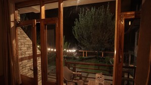 A room with a view of a garden, a wooden bench, and a table with a sign. - Mountainshack Riverside Stay & Cafe (Kullu)