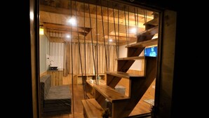 A wooden interior with a staircase, a sofa, and a television. - Mountainshack Riverside Stay & Cafe (Kullu)