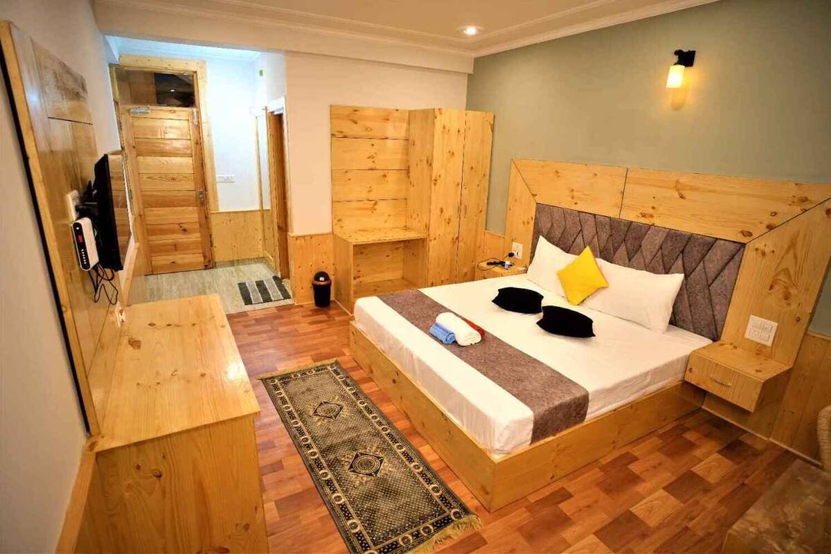 Habitació de fusta amb un llit, un escriptori i una taula petita.