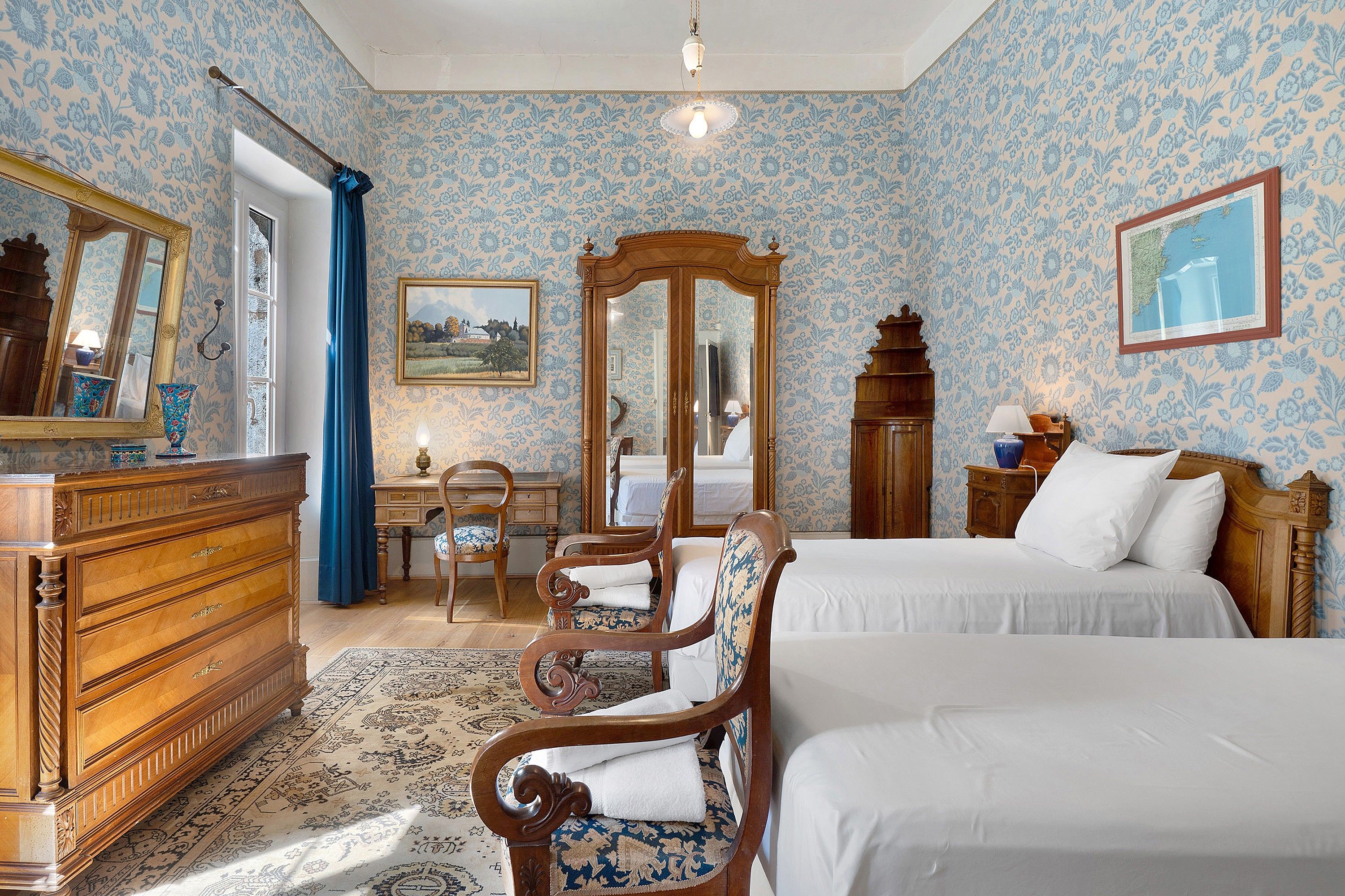 Une chambre avec deux lits, une commode, un bureau, une chaise, un miroir et une carte accrochée au mur.