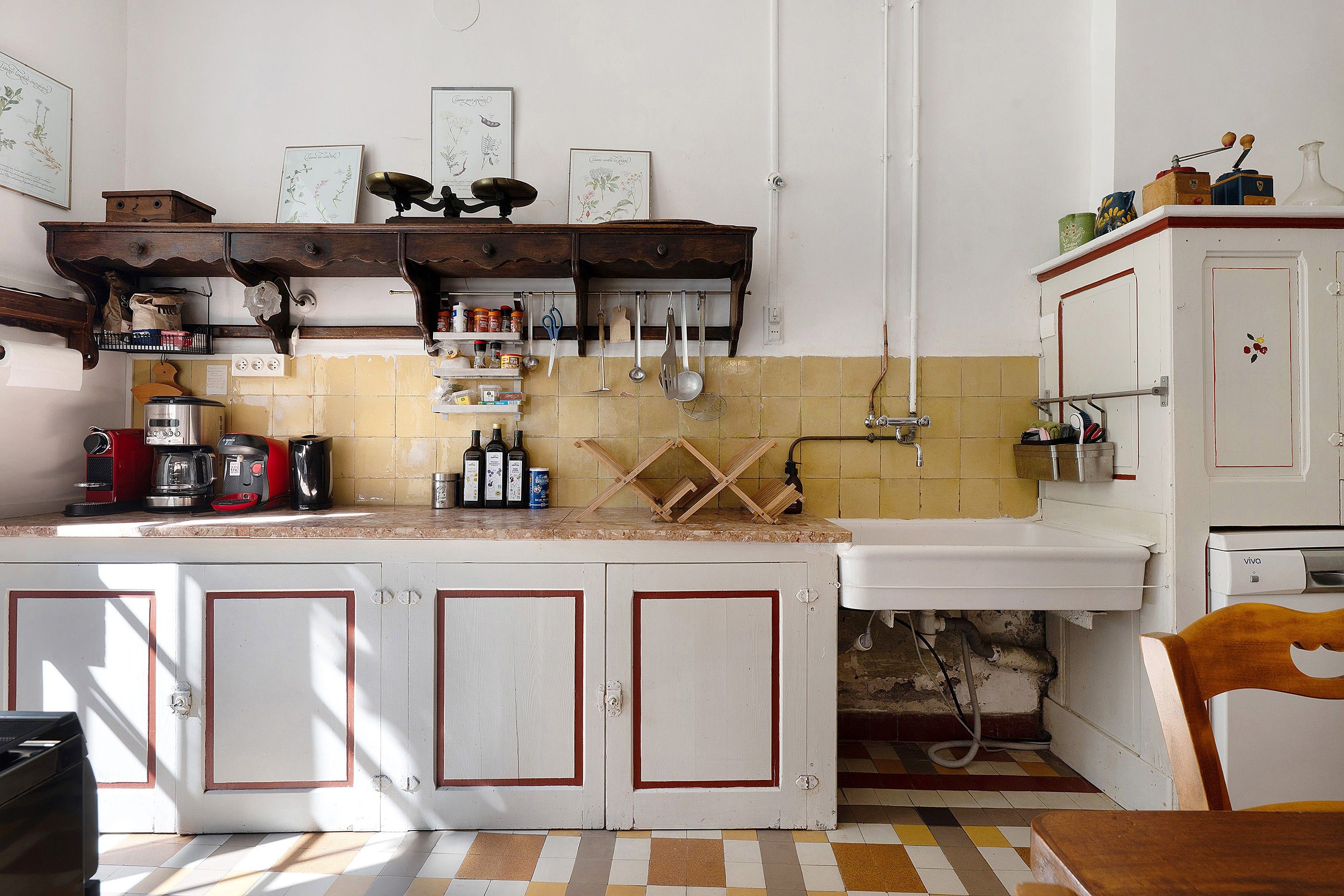 A kitchen with a tiled backsplash, wooden cabinets, and various kitchen utensils.