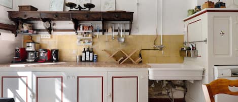 A kitchen with a tiled backsplash, wooden cabinets, and various kitchen utensils.