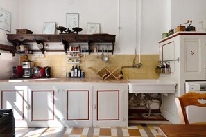 A kitchen with a tiled backsplash, wooden cabinets, and various kitchen utensils. - Château with Private Park – Gîte du Tilleul – Exceptional Setting (Tournon)