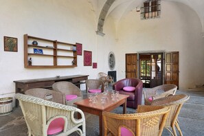 A room with wicker furniture, a wooden table with wine glasses, and a door leading outside. - Château with Private Park – Gîte du Tilleul – Exceptional Setting (Tournon)