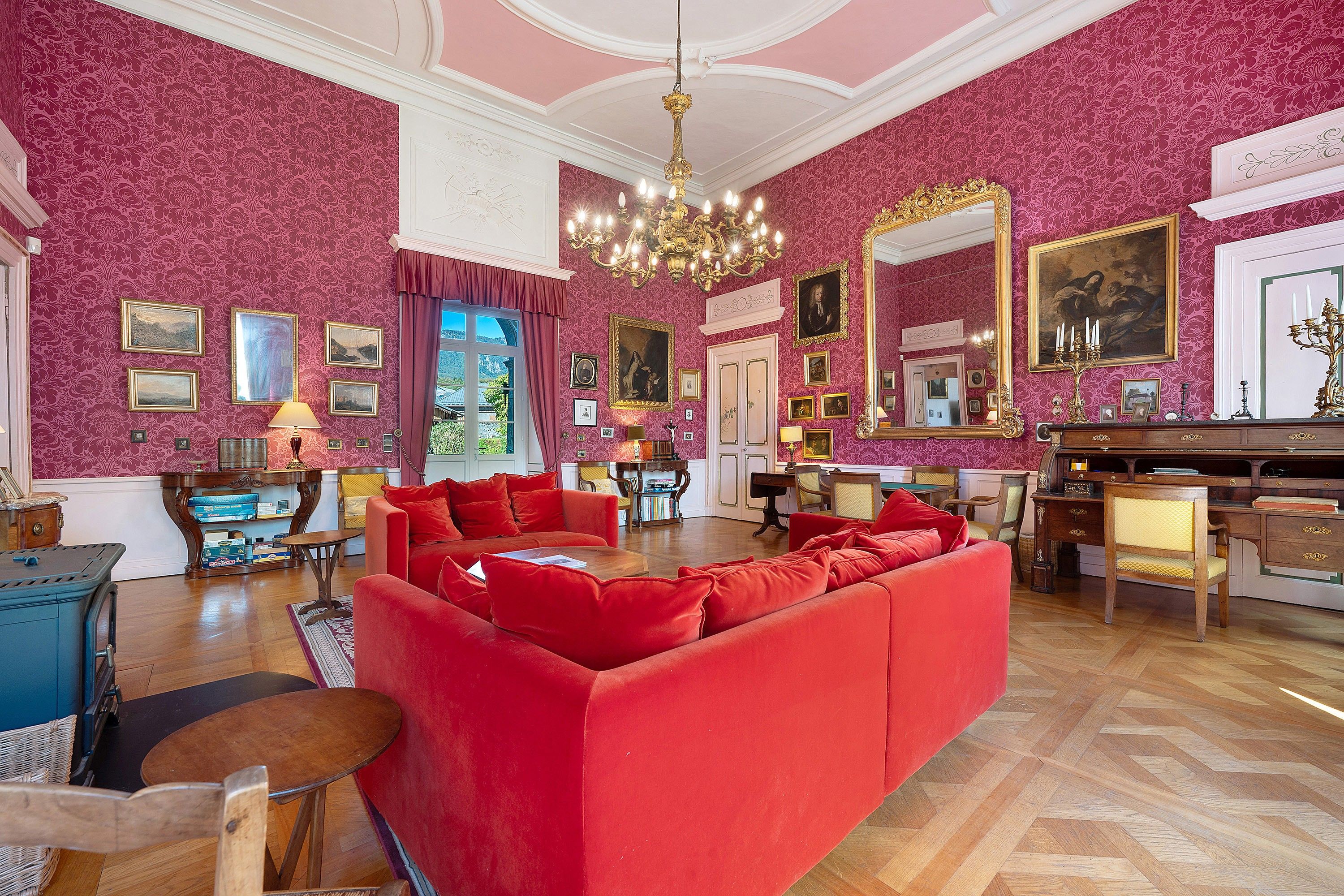 A luxurious room with a red sofa, wooden furniture, and a large mirror.