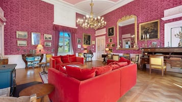 A luxurious room with a red sofa, wooden furniture, and a large mirror.