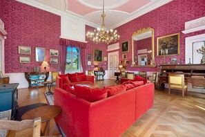 A luxurious room with a red sofa, wooden furniture, and a large mirror. - Château with Private Park – Gîte du Tilleul – Exceptional Setting (Tournon)