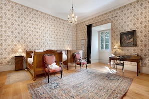 A bedroom with a four-poster bed, a desk, a chair, a rug, and a painting on the wall. - Château with Private Park – Gîte du Tilleul – Exceptional Setting (Tournon)