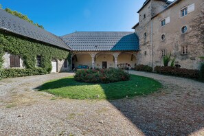 A courtyard with a gravel path, a covered seating area, and a building with a blue roof.
