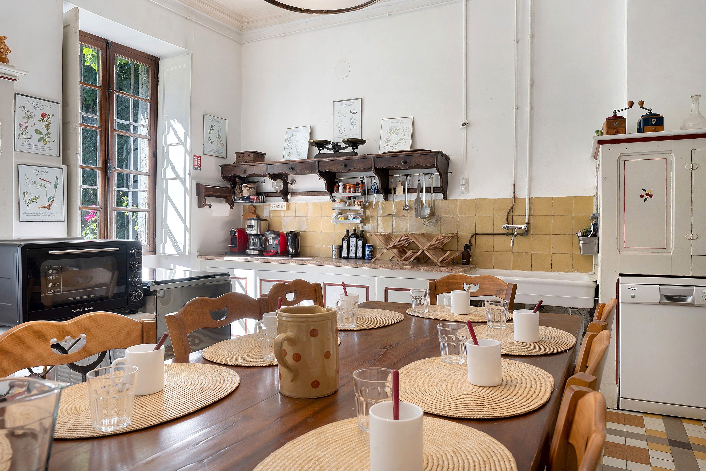 Un coin repas avec une table en bois, dressée pour quatre personnes, entourée de chaises.