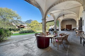 An outdoor patio with stone flooring, wicker furniture, and a view of a mountain. - Château with Private Park – Gîte du Tilleul – Exceptional Setting (Tournon)