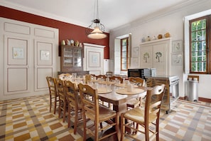 A dining area with a checkered floor, wooden chairs, a central table, and a hanging light fixture. - Château with Private Park – Gîte du Tilleul – Exceptional Setting (Tournon)