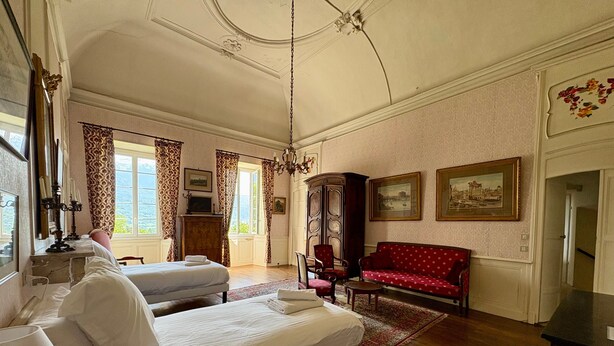 Una habitación con cama, sofá, aparador y candelabro.