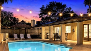 A swimming pool with lounge chairs, a covered patio, and string lights. - Spacious Phoenix Oasis w/ Pool & Game Room (Phoenix)