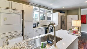 A kitchen with white cabinets, a stainless steel sink, a microwave, and a refrigerator. - Pool Access! Sleek Condo, 2 Mi to Memorial Park (Houston)