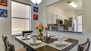 A dining area with a wooden table set for four, a vase with flowers, and artwork on the walls. - Pet-friendly Townhome 9 Mi to Disney w/ Lazy River (Davenport)