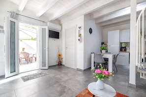 An open-plan living area with a dining table, kitchen, and a sliding door leading to an outdoor space.