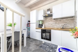 A modern kitchen with white cabinets, a built-in oven, a microwave, and a coffee maker.