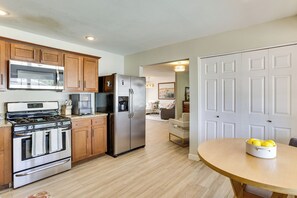 A kitchen with stainless steel appliances, wooden cabinets, and a dining area with a table. - Great for Families! Desert Oasis 2 Mi to Old Town (Scottsdale)