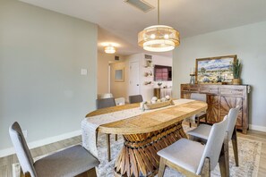 A dining area with a large wooden table, grey upholstered chairs, a hanging light fixture, and a painting on the wall. - Great for Families! Desert Oasis 2 Mi to Old Town (Scottsdale)