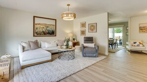 Ein modernes Wohnzimmer mit einer Couch, einem Sessel, einem Couchtisch und Kunstwerken an den Wänden.
