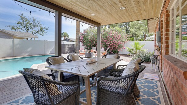 Eine Terrasse im Freien mit Pool, Korbmöbeln und einer Backsteinmauer.