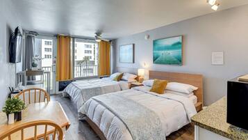 Une chambre d’hôtel avec deux lits, une table à manger, des chaises, un téléviseur et un balcon avec des rideaux.