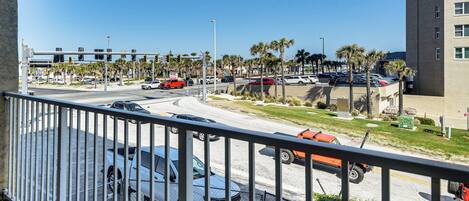 A view of a parking lot with several cars, a building with multiple floors, and palm trees.