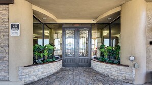 L’entrée d’un hôtel avec une façade en pierre, un panneau indiquant « NE PAS STATIONNER DEVANT L’ENTRÉE » et un autre panneau indiquant un accès 24 heures sur 24.