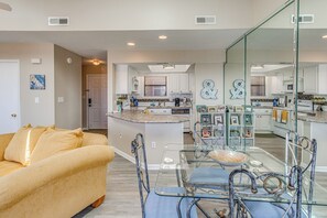 A modern kitchen with white cabinets, a central island, and a glass dining area.