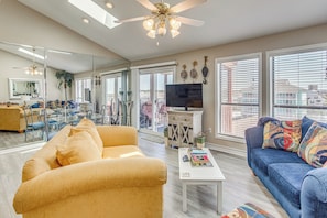 A living room with a sofa, coffee table, TV, and a balcony with a view. - Walk to Beach! North Myrtle Beach Condo w/ Balcony (North Myrtle Beach)