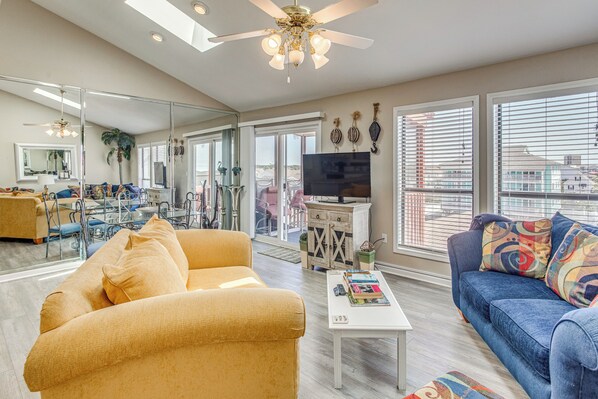 A living room with a sofa, coffee table, TV, and a balcony with a view.