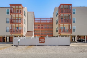 A multi-story building with balconies, a gated entrance, and a sign for condo owners and guests. - Walk to Beach! North Myrtle Beach Condo w/ Balcony (North Myrtle Beach)