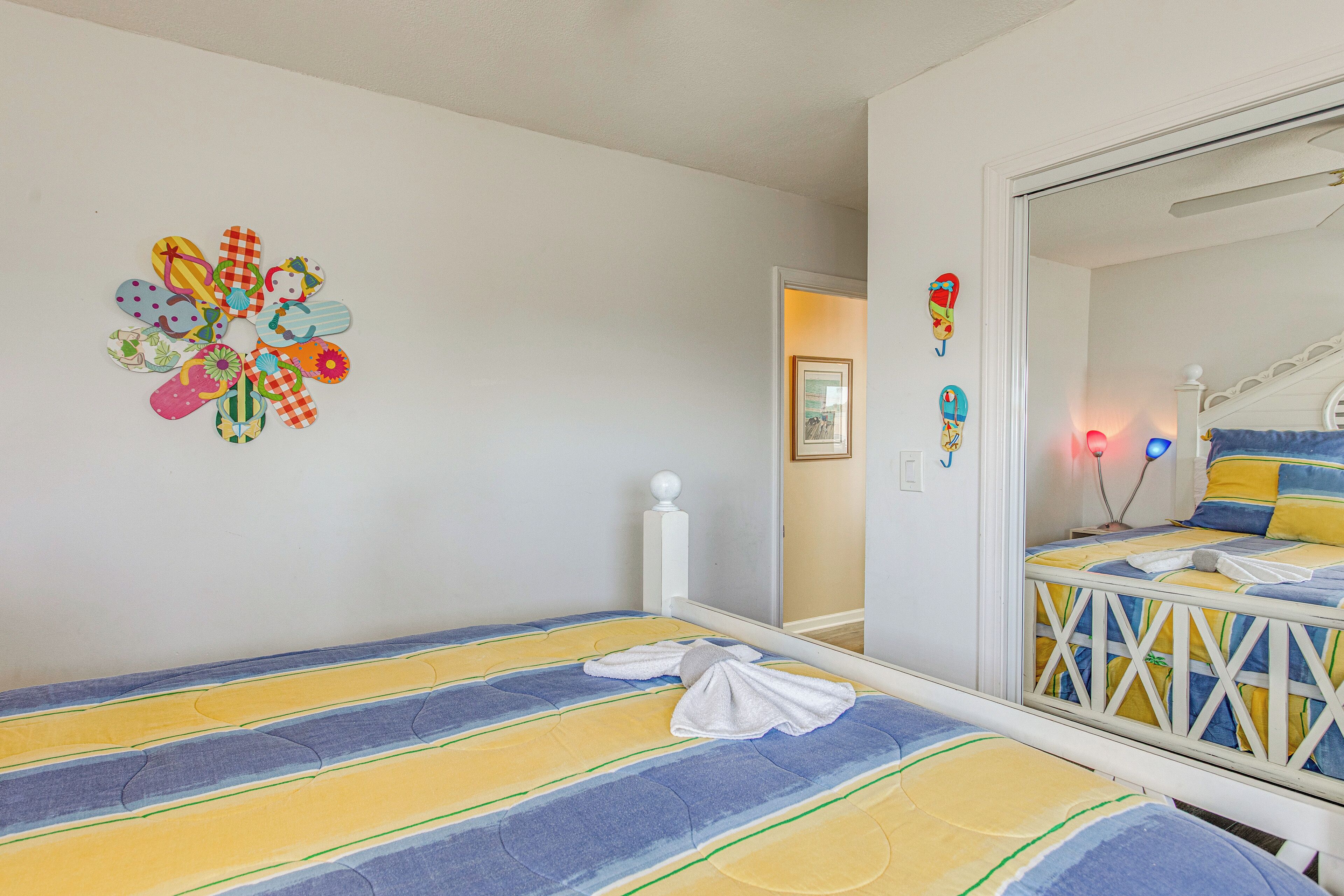 A bedroom with a bed, a wall decoration, a mirror, and a door leading to another room.