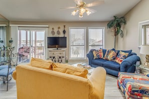 A living room with a sofa, armchairs, a TV, and a ceiling fan.