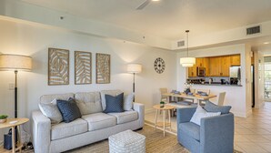 A living room with a sofa, ottoman, and chairs, a dining area with a table and chairs, and a kitchen with cabinets and appliances. - Walk to Bahia Beach! Canal-front Townhome w/ Views (Ruskin)